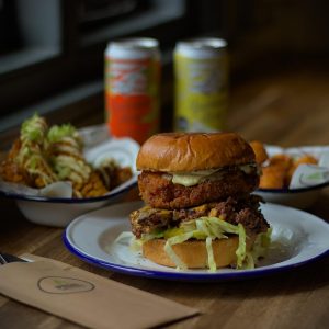 Burger and Sides on table with drinks from new summer menu