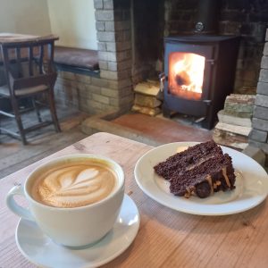 Coffee and cake in front of lit wood burner.